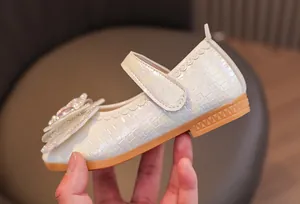 Detailed view of white pearlescent Mary Jane shoes with woven texture and bow detail