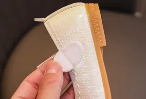 Detail of cream girls Mary Jane shoe showing adjustable hook-and-loop strap closure
