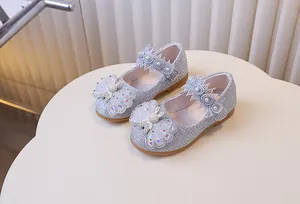 Détail de chaussures Mary Jane argentées avec nœuds en dentelle et perles pour petites filles
