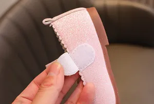 Détail de chaussures Mary Jane à paillettes roses avec fermeture velcro et bordure ondulée