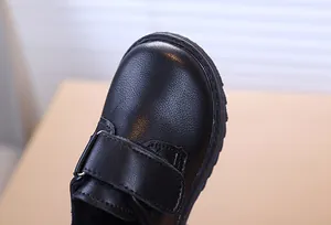 Gros plan sur la pointe ronde et le cuir grainé de ces chaussures noires pour garçon
