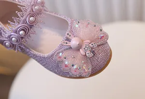Détail d'une chaussure rose scintillante pour fille avec nœud et fleurs en dentelle