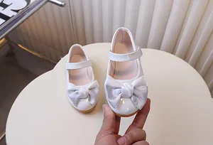 Detail van witte laklederen Mary Jane schoenen met een glinsterende pailletten strik en band