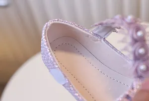 Détail d'une chaussure Mary Jane rose pailletée avec rose en satin et perle sur bride
