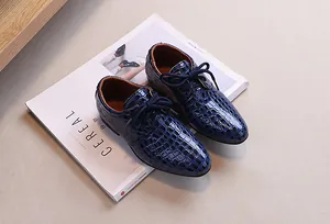 Classic blue crocodile pattern leather boys oxford shoes placed on a magazine