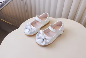 Detailoverzicht van witte lakschoenen voor meisjes met zilveren strik en klittenband