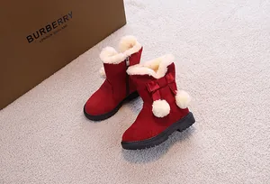 Dettaglio di stivali da neve rossi per bambini con bordo in ecopelliccia e fiocco a pompon