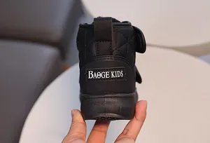 Détail de bottes d'hiver noires pour enfants avec motif matelassé et écusson badge