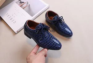 Detail of boys navy blue faux crocodile embossed patent leather dress shoes with laces