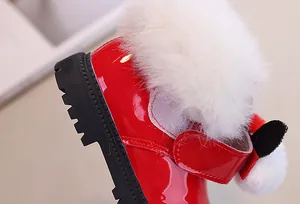 Dettaglio di stivali da neve rossi in vernice per bambini con finto pelo bianco e suola