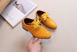 Detail of yellow boy's dress shoes with crocodile texture and classic round laces
