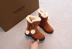 Dettaglio di stivali da neve marroni da bambina con fodera in peluche e fiocco laterale