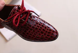 Detailed close-up of dark red crocodile embossed leather formal dress shoes for boys