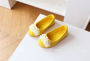Close-up of yellow suede girl's flats with 3D gauze flowers and pearl details