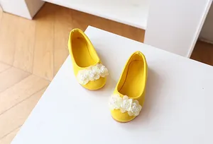 Detail of yellow suede girls princess shoes with white 3D flowers and pearls