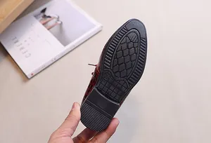 Detailed view of non-slip black rubber sole with size 26 marking on boys dress shoes