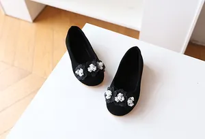 Detail of black suede girls' flats featuring three fabric flowers with pearl centers