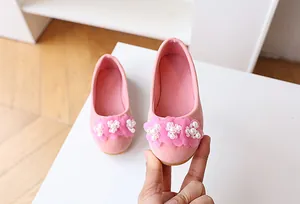 Close-up of pink suede girl's princess shoes with fabric flowers and pearl accents
