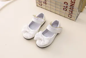 Detail of white patent leather Mary Jane shoes with lace ribbon and large bow decoration