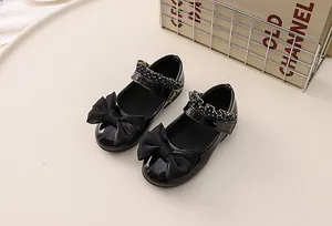 Detail of girls' black patent leather Mary Janes with large bow and polka dot strap