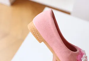 Close-up of pink suede girl's flats showing pearl floral details and non-slip sole