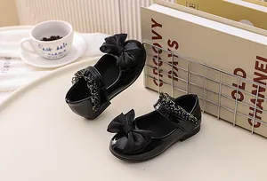 Detail of glossy black patent leather girls Mary Janes with ribbon bow and polka dot trim