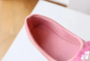 Detailed close-up of pink suede girl shoes with pearl flowers and soft inner fabric