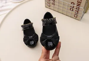Detail of black patent leather girls' Mary Jane shoes with ribbon bow and polka dot trim