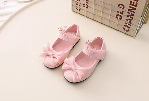 Close-up of pink patent leather Mary Jane shoes with large satin bow and lace details