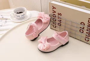 Close-up of pink patent leather girls shoes with large bow and lace trim details