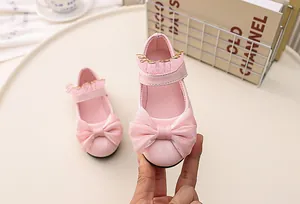 Close-up of pink princess shoes featuring a large tulle bow and delicate lace trim