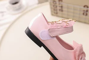 Detailed view of pink patent leather girls shoe with lace trim and bow accent