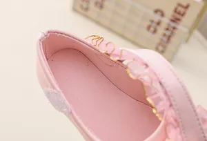 Detail of soft pink girls princess shoe featuring delicate lace trim and glossy finish