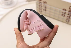 Close-up of flexible soft sole being bent on pink bow girls princess shoes