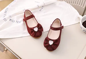 Makro-Detail roter Glitzer-Mary-Janes für Mädchen mit großer Schleife und Herz-Kristall