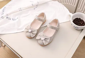 Detail von champagnerfarbenen Glitzer-Mary-Janes mit Schleife und Herz-Edelstein