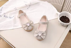 Detailansicht der champagner-goldenen Pailletten-Mary-Janes mit Schleife und Strass