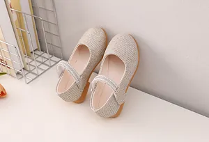 Close-up of champagne Mary Jane shoes with glitter fabric and pearl rhinestone strap