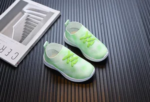 Gros plan de baskets en maille respirante pour enfants au design dégradé vert et blanc