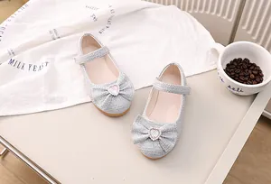Detail von silbernen Pailletten Mary Janes mit Glitzerschleife und pinkem Herz-Edelstein