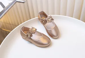 Close-up of champagne Mary Jane shoes for girls with floral accents and pearl centers