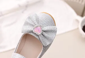 Makro-Detail von silbernem Pailletten-Prinzessinnenschuh mit glitzernder Schleife und Herz