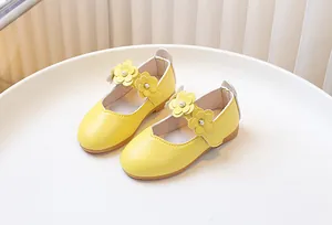 Detail of yellow girls Mary Jane shoes featuring three leather flowers and faux pearls