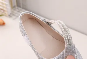 Close-up of shiny silver sequins and rhinestone strap detail on girls princess shoes
