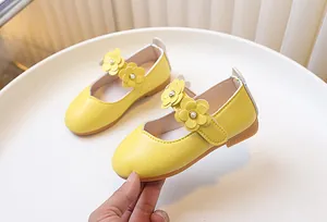 Detail of yellow girl's Mary Jane shoes with 3D flowers and faux pearl center decorations