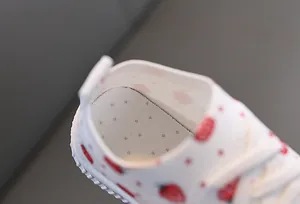 Détail de chaussures blanches pour bambins avec imprimé fraise et semelle aérée
