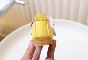 Detail of yellow toddler shoes showing non-slip rubber sole and lychee leather texture