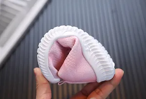 Chaussures bébé roses en maille montrant la semelle souple flexible à 180 degrés