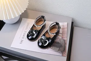 Detail von schwarzen Lack-Mary-Janes für Mädchen mit Perlen, Spitze und Schleife