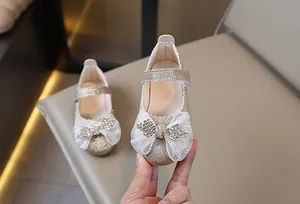 Detalle de zapatos Mary Jane de lentejuelas doradas con lazo grande y strass para niña